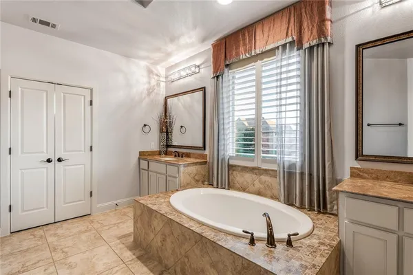 a bathroom with a granite countertop tub sink and mirror