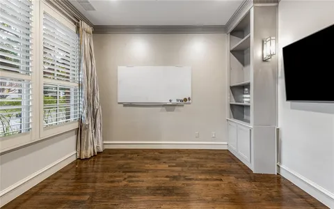 a view of an empty room with wooden floor and a window