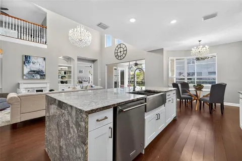 a kitchen with stainless steel appliances granite countertop a stove a sink and white cabinets with wooden floor