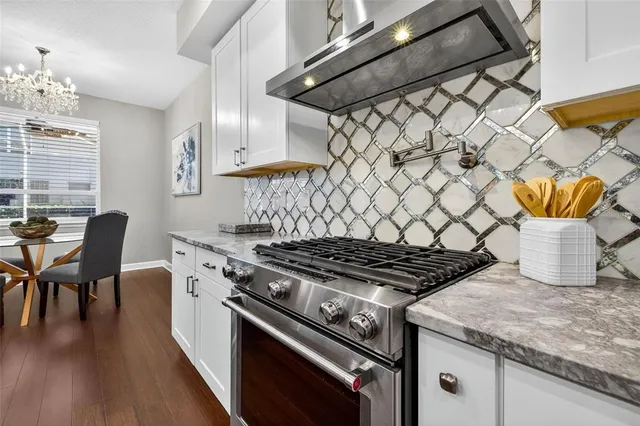 a large white kitchen with lots of counter space and stainless steel appliances
