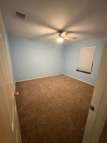 an empty room with a chandelier fan and closet
