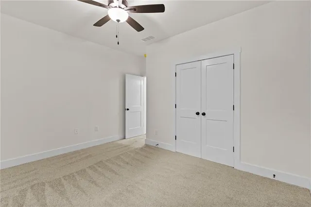 a view of an empty room with closet and a window