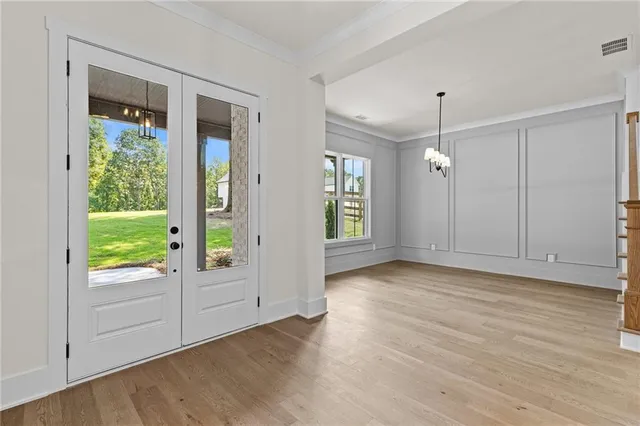 a view of an empty room with window and hardwood floor