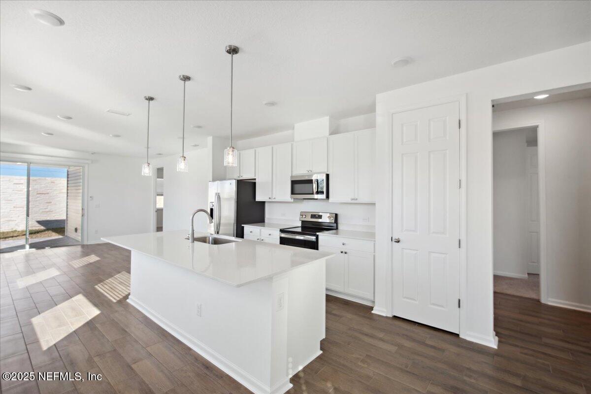 7212 Red Timber Road Jacksonville, FL 32244 - Photo 8 of 31 a kitchen with stainless steel appliances kitchen island granite countertop a refrigerator a sink a stove and white cabinets with wooden floor