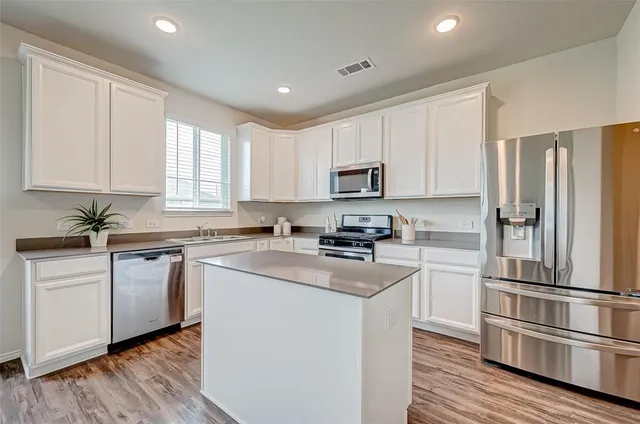 a kitchen with cabinets stainless steel appliances a sink and wooden floor