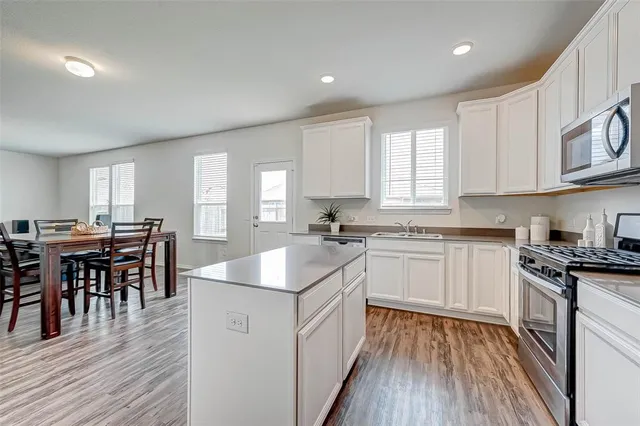 a kitchen with a sink stove cabinets and wooden floor
