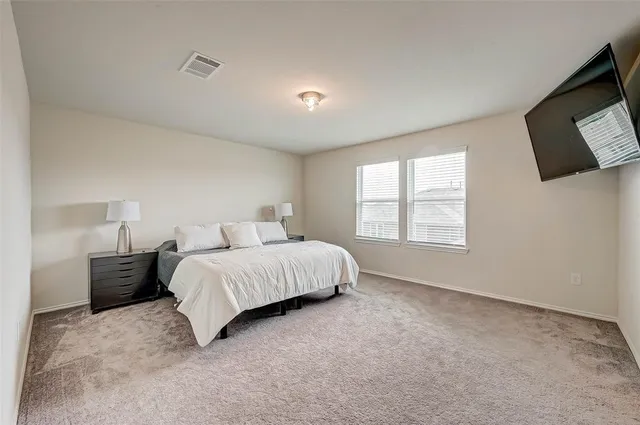a spacious bedroom with a bed and a flat screen tv