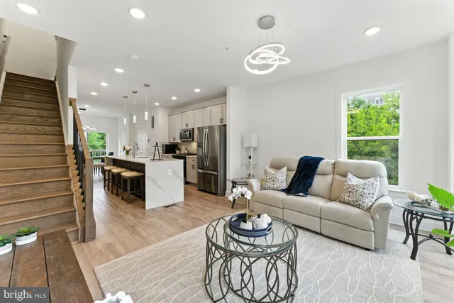 a living room with furniture kitchen area and a wooden floor