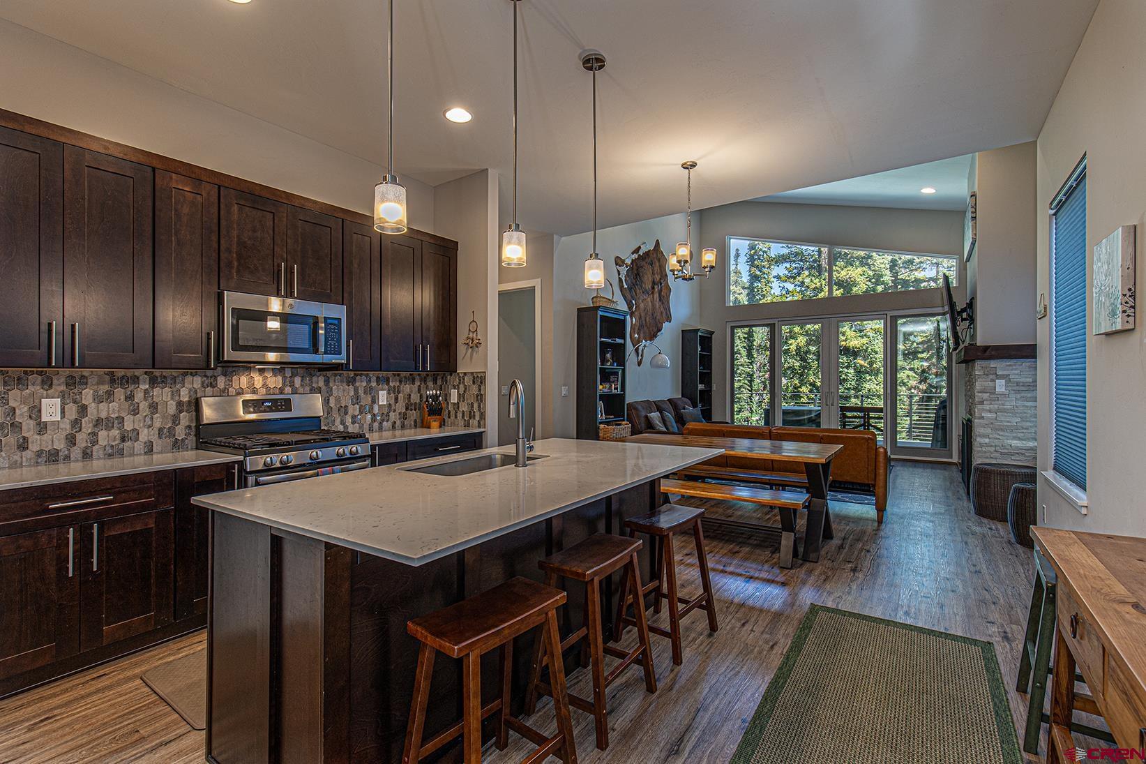 107 Tacoma Drive Durango, CO 81301 - Photo 3 of 29 a kitchen with stainless steel appliances granite countertop a stove a refrigerator a sink a dining table and chairs with wooden floor