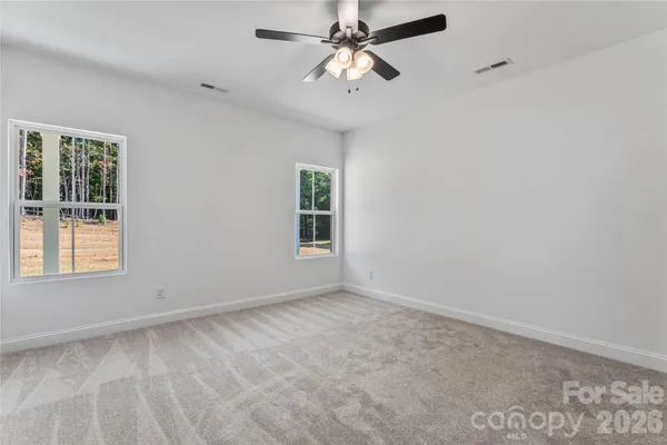 a view of empty room with window and ceiling fan