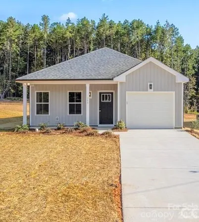a front view of house with yard and trees in the background