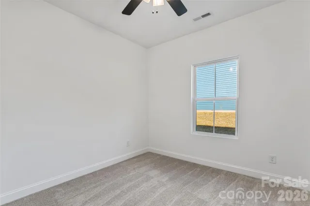 an empty room with a window and ceiling fan