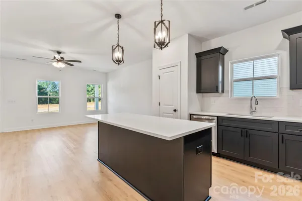 a kitchen with a sink chandelier and wooden floor