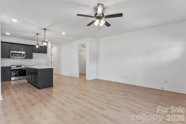 a kitchen with kitchen island a counter top space appliances and a ceiling fan