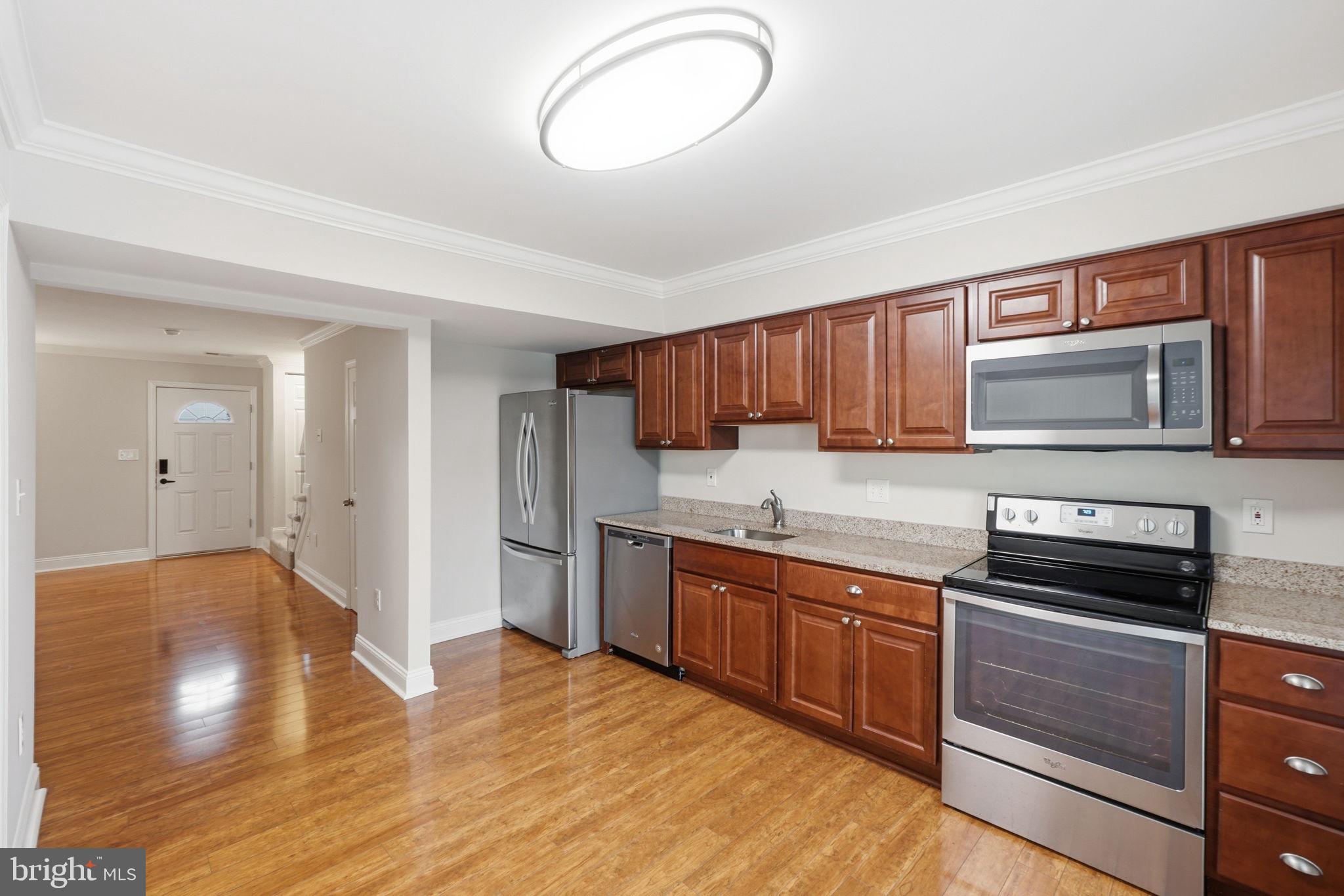 524 Lancaster Place, Unit 524 Frederick, MD 21703 - Photo 7 of 28 a kitchen with stainless steel appliances granite countertop a stove a sink dishwasher and a microwave oven with wooden floor