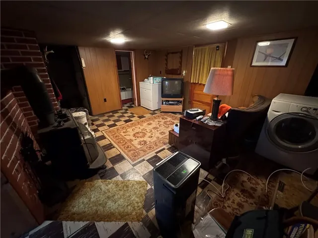 a living room with a black white checkered floor with couches a flat screen tv and a stove