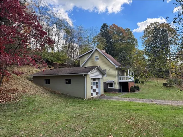 a view of a house with a big yard and large trees