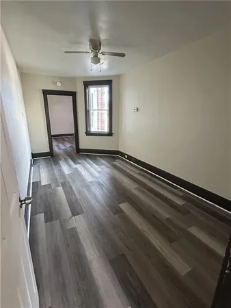 a view of an empty room with wooden floor and a window