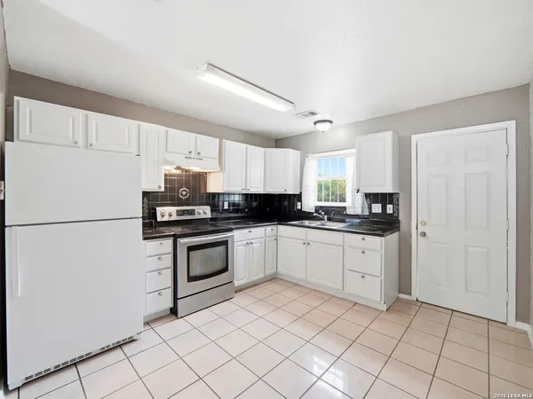 a kitchen with granite countertop white cabinets and white appliances