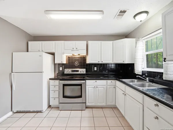 a kitchen with a sink a stove a refrigerator and white cabinets