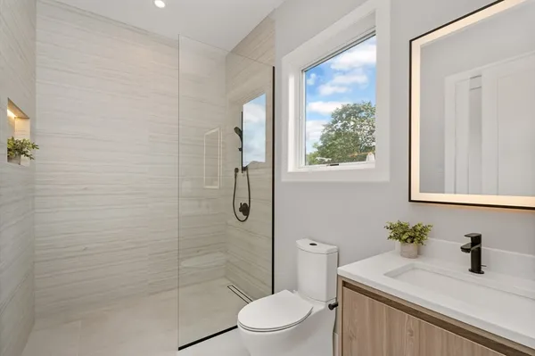 a bathroom with a sink a toilet a window and shower