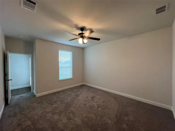 an empty room with windows and chandelier fan