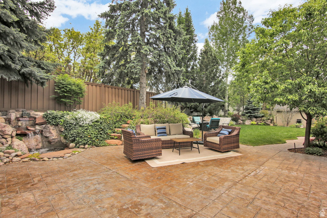 1350 Canyon Park Road Bountiful, UT 84010 - Photo 3 of 38 Expansive stamped concrete patio featuring a rock waterfall, mature evergreen trees, a manicured lawn, and a privacy fence