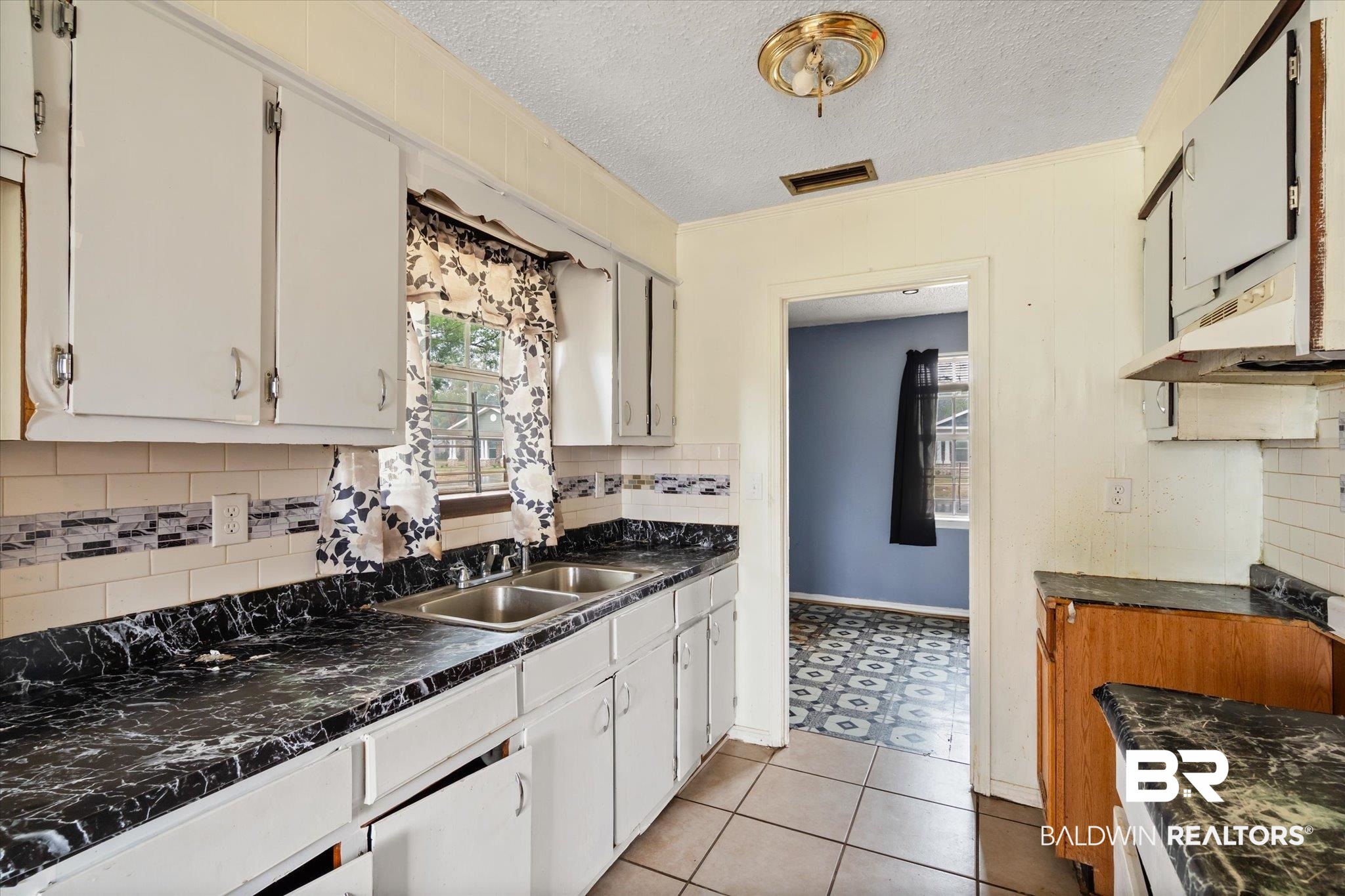 313 West 4th Avenue Foley, AL 36535 - Photo 5 of 20 Kitchen with sink, a textured ceiling, decorative backsplash, and white cabinets