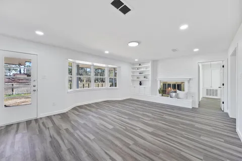 a view of an empty room with a window and wooden floor