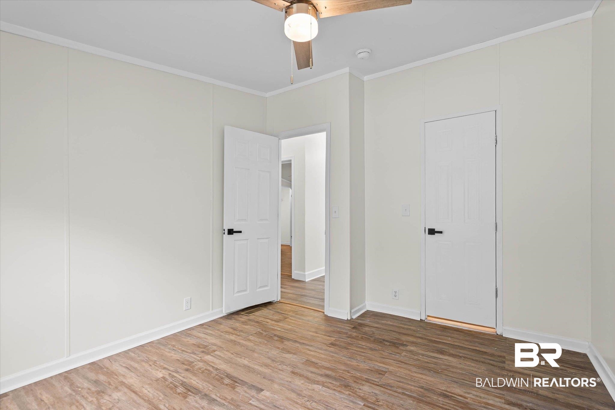 9230 McLeod Road Mobile, AL 36695 - Photo 14 of 20 Spacious room featuring wood-finish flooring, white paneled walls, and white trim