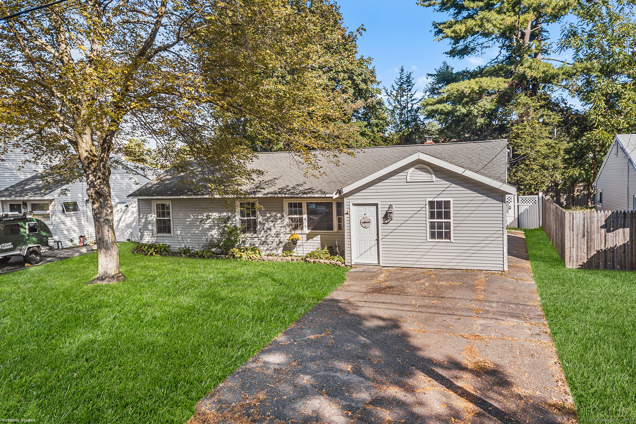 a view of a yard in front of a house with plants and large tree