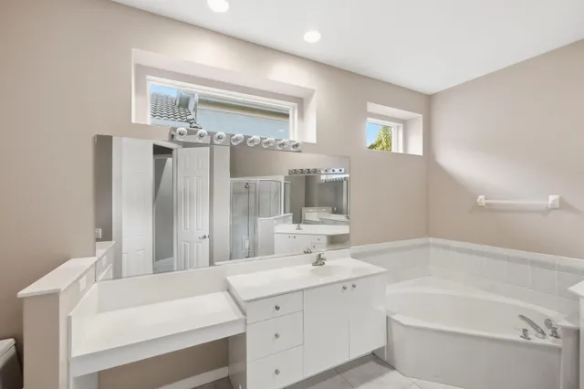 a large white bathroom with a large tub sink vanity and granite