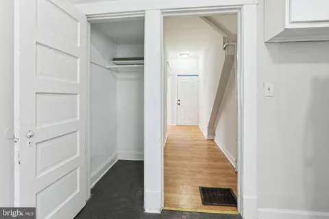 a view of a hallway with wooden floor and a bathroom
