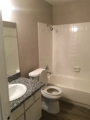 a bathroom with a granite countertop toilet sink and mirror