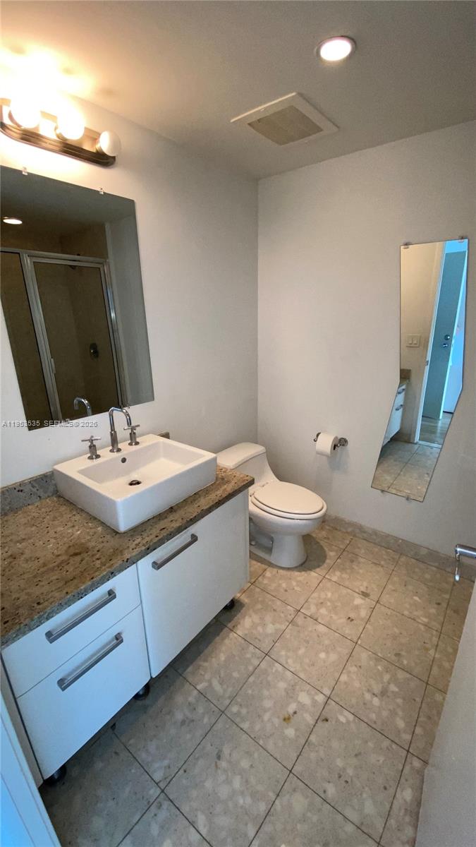 185 Southwest 7th Street, Unit 3706 Miami, FL 33130 - Photo 17 of 26 a bathroom with a granite countertop sink a toilet and mirror