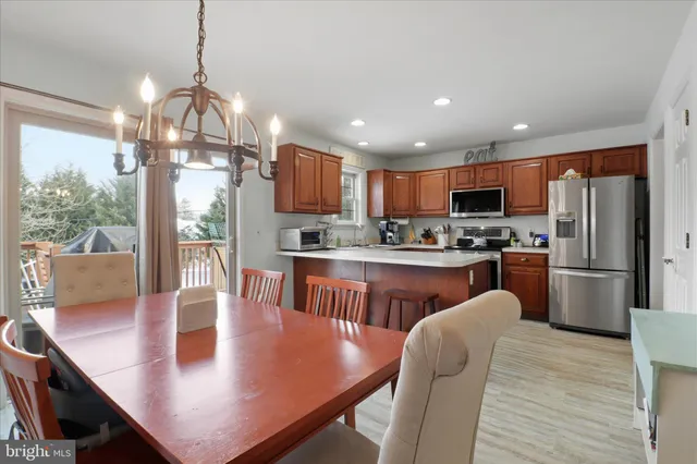 a kitchen with stainless steel appliances granite countertop a refrigerator a stove top oven a sink dishwasher a dining table and chairs with wooden floor