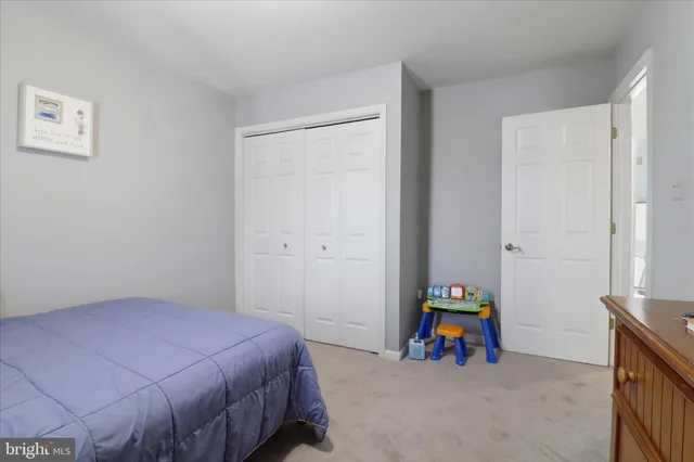 a bedroom with a bed a desk and flowerpot
