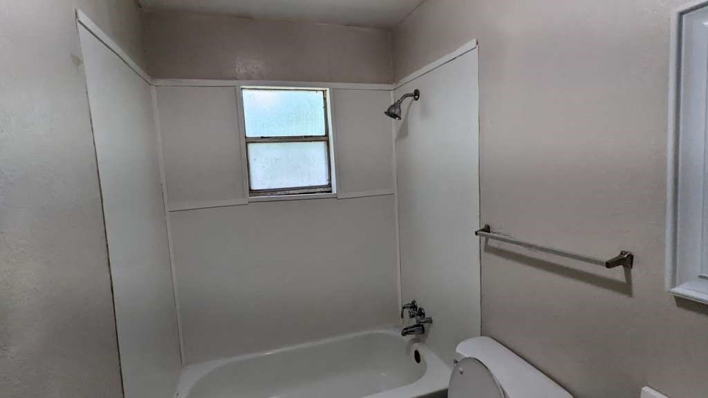 215 Blackshear Street Tomball, TX 77375 - Photo 10 of 12 a bath room with a toilet and a bath tub