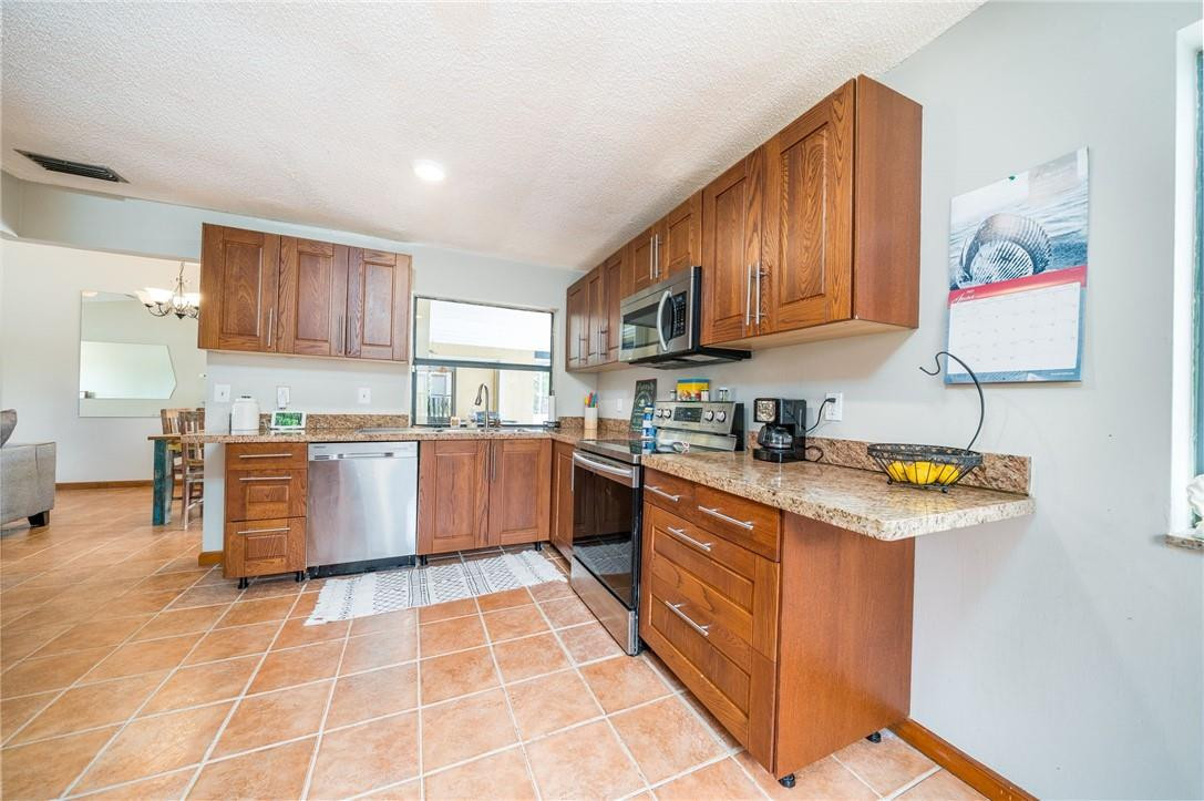 22534 Southwest 7th Street Boca Raton, FL 33433 - Photo 10 of 35 a kitchen with stainless steel appliances granite countertop a stove top oven a sink dishwasher and cabinets with wooden floor