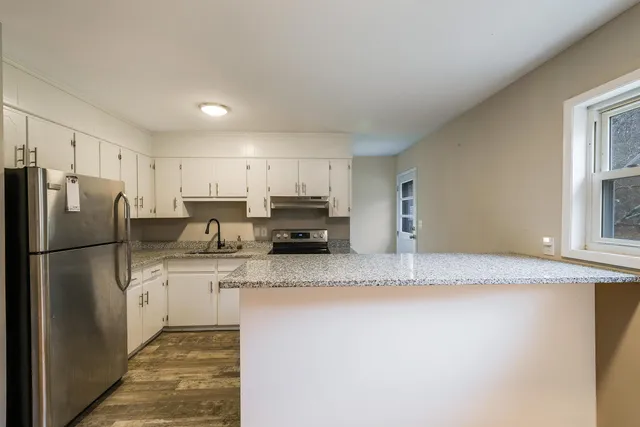 a kitchen with stainless steel appliances granite countertop a refrigerator a stove a sink a microwave and white cabinets