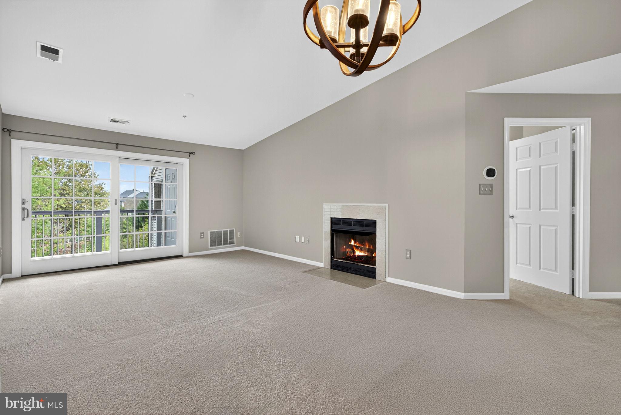 44084 Natalie Terrace, Unit 301 Ashburn, VA 20147 - Photo 14 of 59 an empty room with a fireplace and a large window