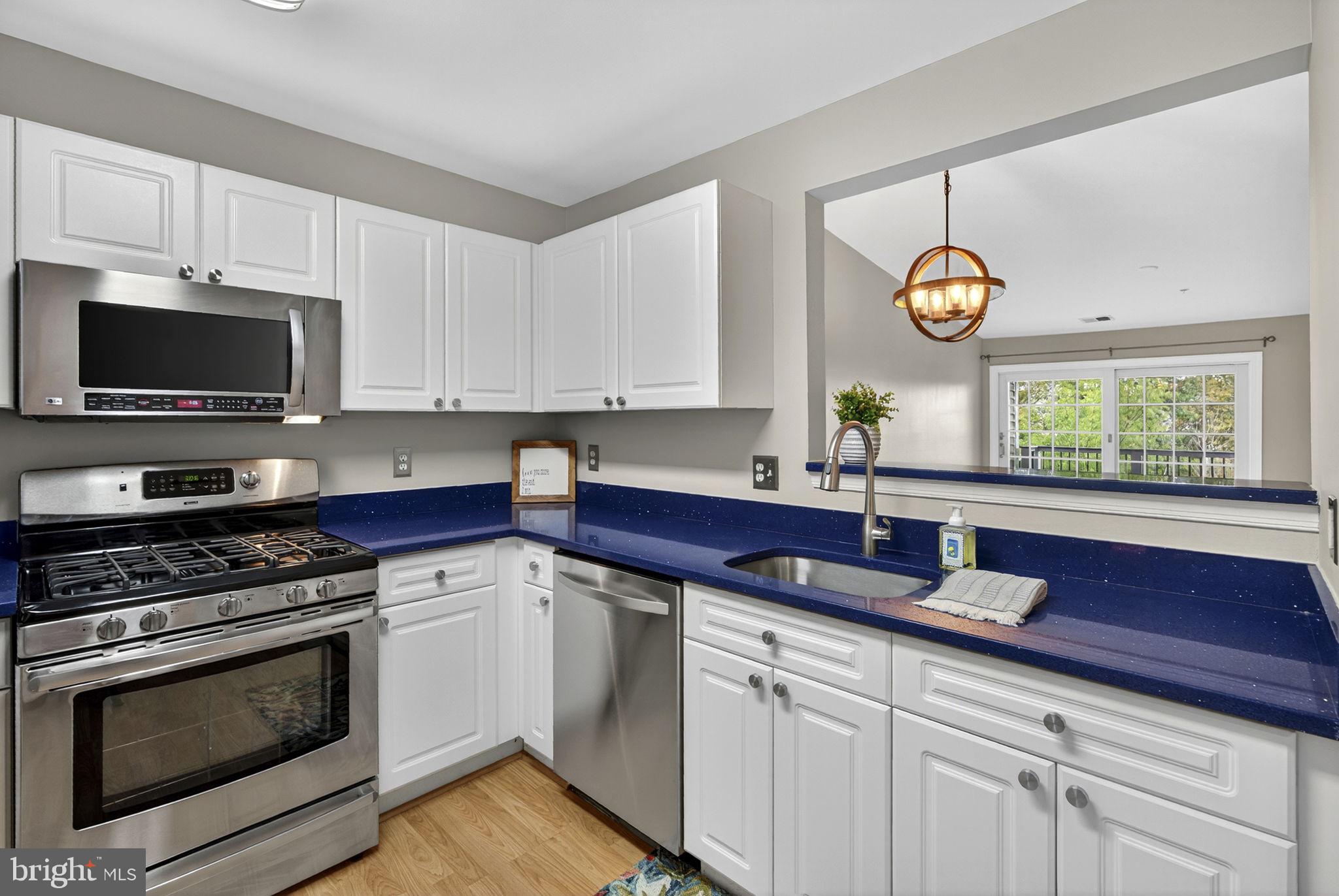 44084 Natalie Terrace, Unit 301 Ashburn, VA 20147 - Photo 34 of 59 a kitchen with stainless steel appliances granite countertop a sink a stove a microwave cabinets and a window