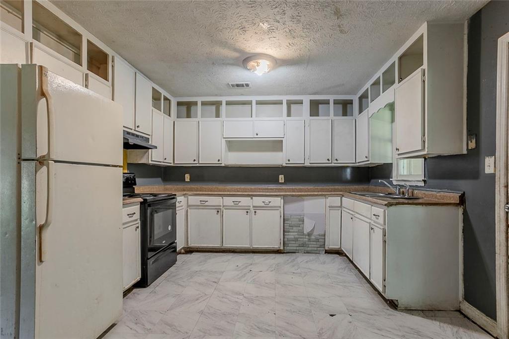 926 Bell Road Southeast Conyers, GA 30094 - Photo 4 of 32 a kitchen with granite countertop a refrigerator stove top oven and white cabinets