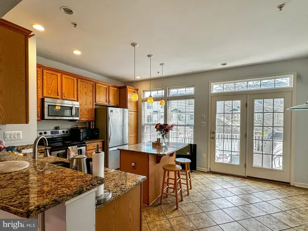 a kitchen with stainless steel appliances granite countertop a stove top oven a sink dishwasher a dining table and chairs with wooden floor
