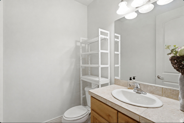 7772 South Rustic Cove Midvale, UT 84047 - Photo 22 of 39 Clean and functional bathroom featuring a wood-finish vanity with an oval porcelain sink, quartz countertop, and chrome faucet