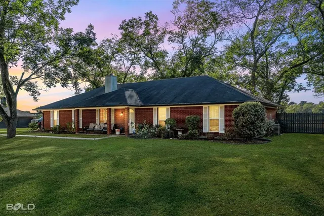 a view of a big house with a big yard and large trees