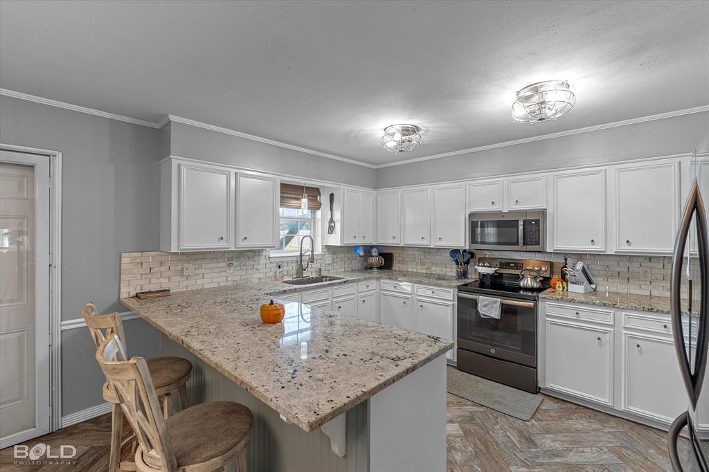 3804 Farmridge Road Keithville, LA 71047 - Photo 20 of 36 a kitchen with a stove a sink a microwave a dining table and chairs