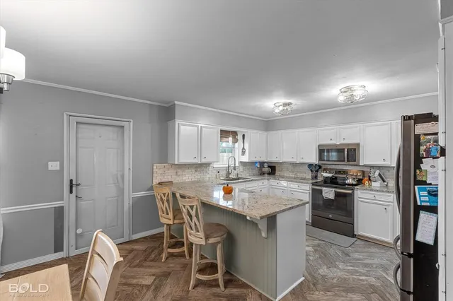 a kitchen with stainless steel appliances a sink a stove a refrigerator cabinets and dining table