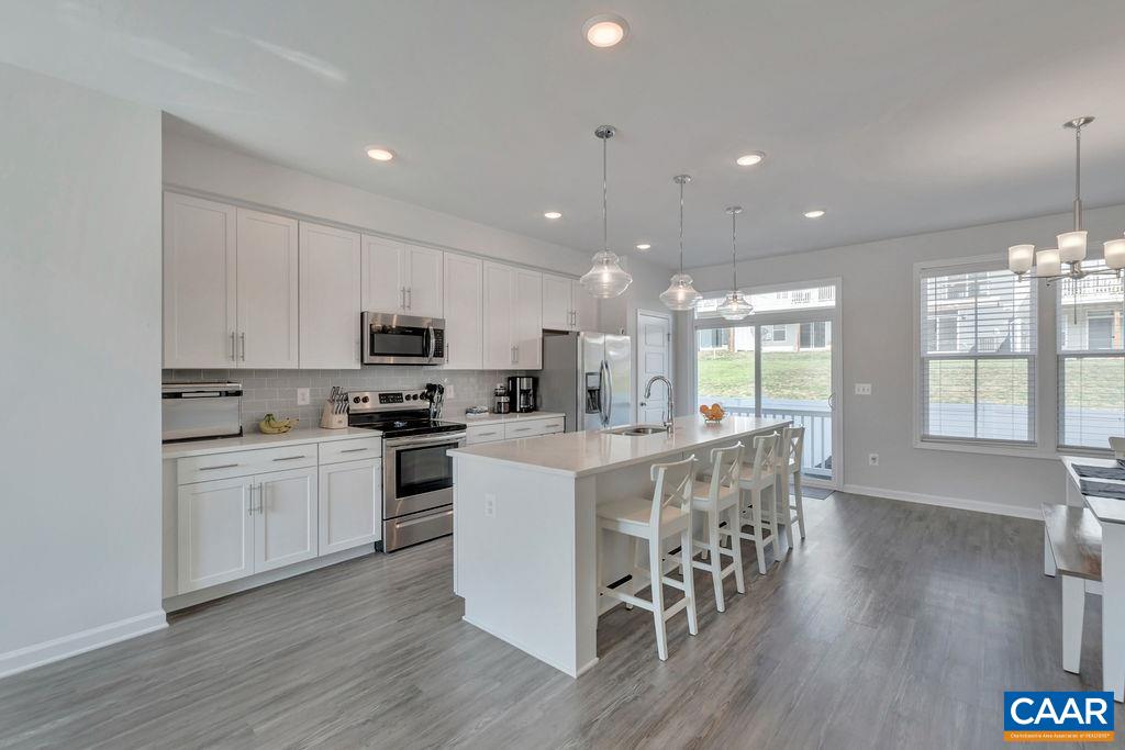 2176 Avinity Loop Charlottesville, VA 22902 - Photo 11 of 50 a kitchen with stainless steel appliances granite countertop a refrigerator a stove top oven a sink dishwasher and white cabinets with wooden floor