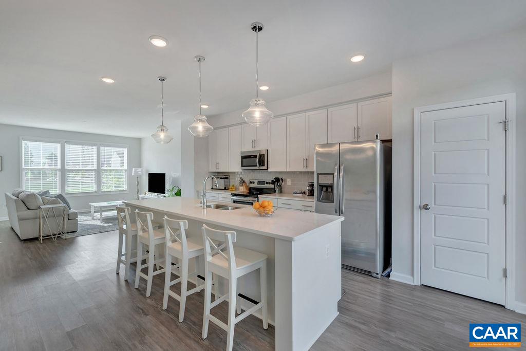2176 Avinity Loop Charlottesville, VA 22902 - Photo 13 of 50 a kitchen with stainless steel appliances kitchen island granite countertop a refrigerator a stove a sink a dining table and chairs with wooden floor